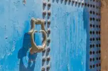 grey door knocker on blue wooden door with rivets