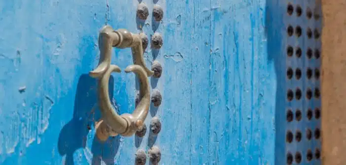 grey door knocker on blue wooden door with rivets